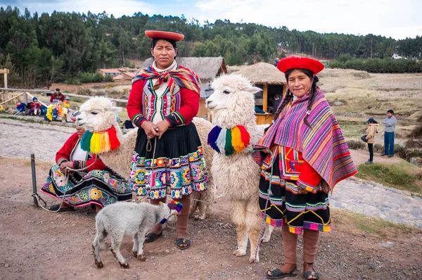 View of women in national clothing with lamas on the background of Sacsayhuaman landscape with tourists — Stock Photo, Image