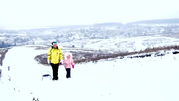 Mom with daughter carrying sledge — Stock Video