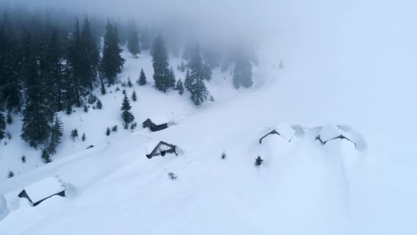 Vista superior de cabañas cubiertas de nieve en las montañas — Vídeos de Stock