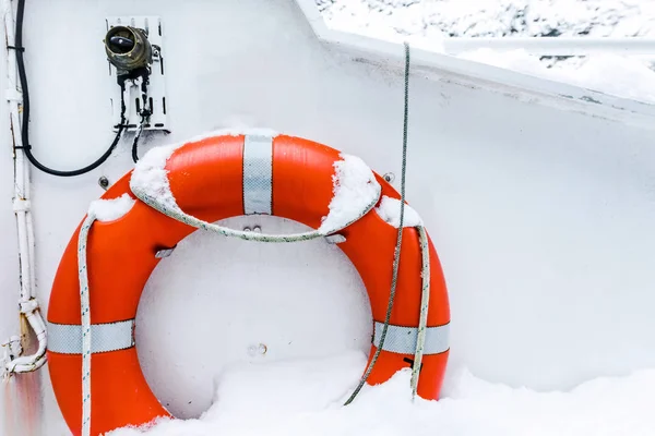 Orange lifebuoy ring on white boat in winter — Stock Photo, Image