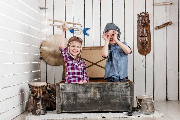 Petite fille avec avion en bois à la main et garçon en chapeau de pilote — Photo