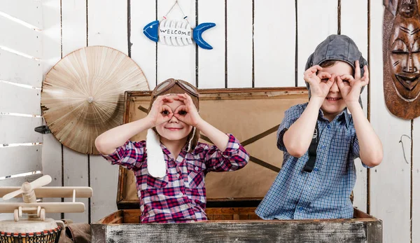 Dos niños pequeños en sombreros piloto haciendo gafas con las manos — Foto de Stock