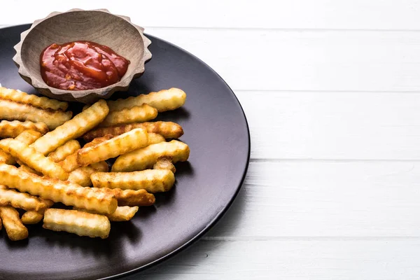 Patatas francesas con ketchup en plato negro —  Fotos de Stock