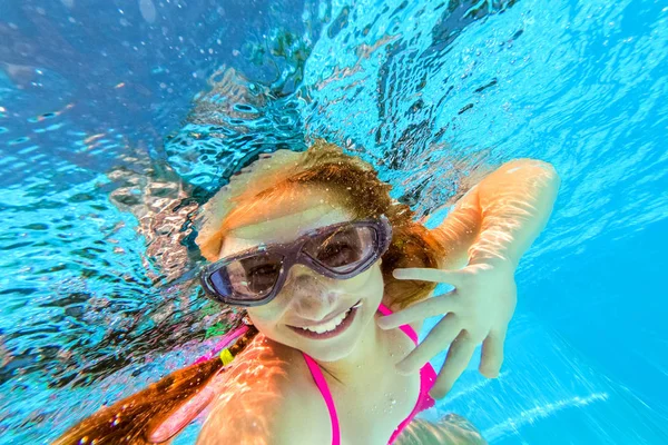 Smiling girl swimming underwater in pool — Stock Photo, Image