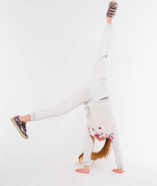 Petite fille active sur fond blanc faisant un handstand — Photo