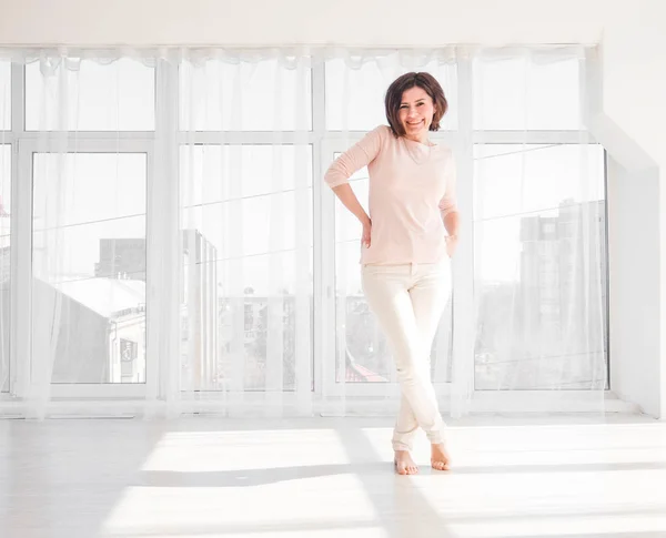 Stylish woman standing in a bright white room — Stock Photo, Image