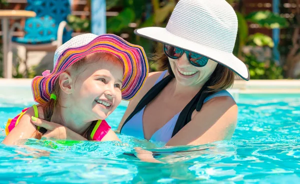 Sonriente mamá sosteniendo hija en la piscina —  Fotos de Stock