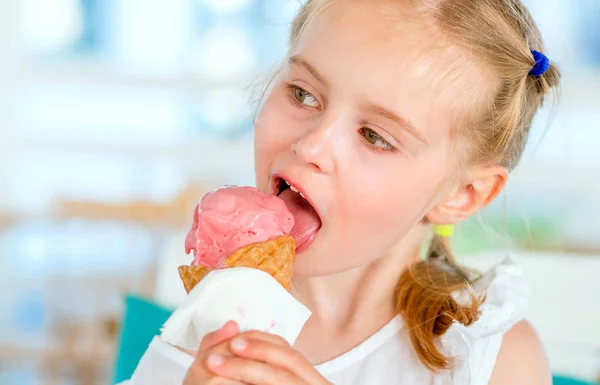 Little blond girl eating pink ice cream — Stock Photo, Image