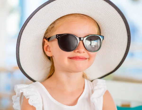 Kleines lächelndes blondes Mädchen mit schwarzer Sonnenbrille — Stockfoto