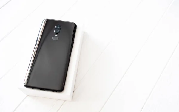 Smartphone Moderno Negro Con Una Caja Blanca Mesa Madera Blanca —  Fotos de Stock