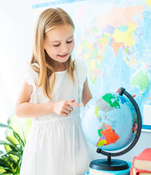 Pequeña mirada de colegiala apuntando al globo — Foto de Stock