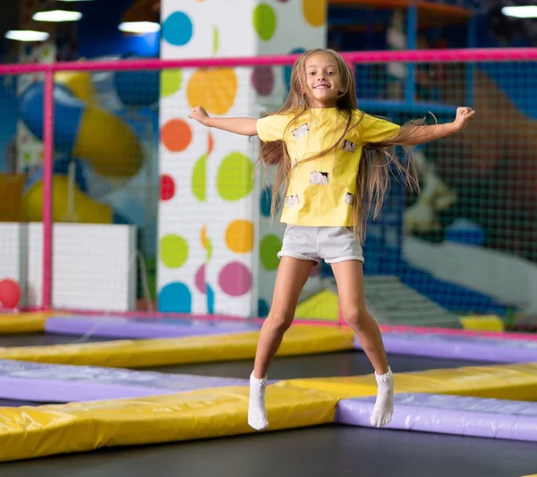 Kleines aufgeregtes Mädchen beim Sprung auf dem Trampolin fotografiert — Stockfoto