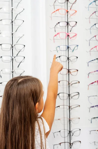 Little blond girl pointing on the glasses on the showcase — Stock Photo, Image