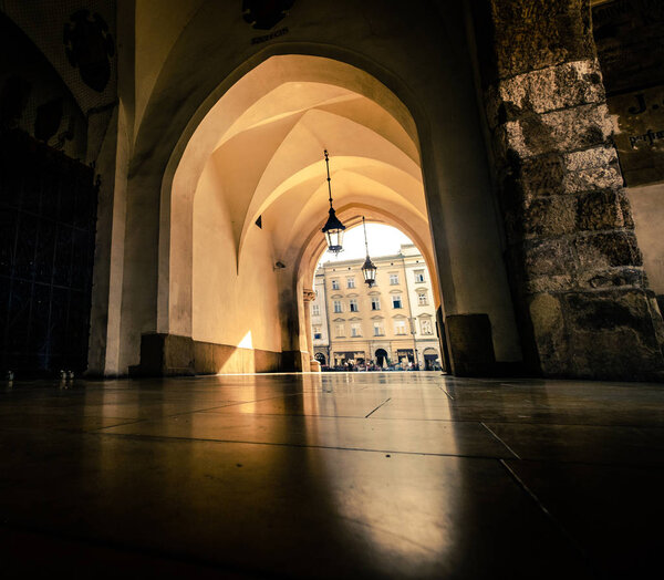 Sunshine view of Krakow city square through the light archway
