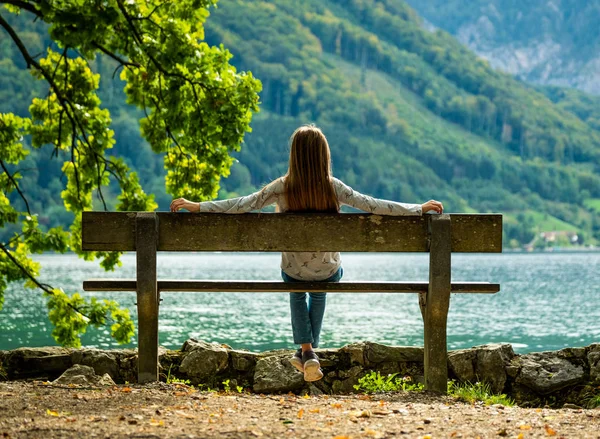 Little girl sitting on the bench and looking on the river scenery — Stock Photo, Image