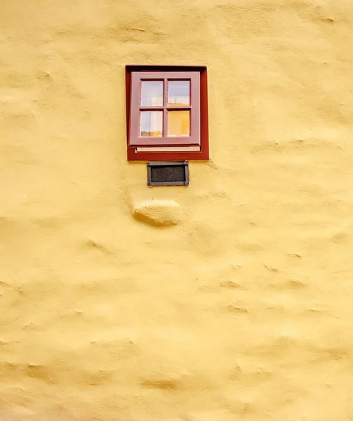Pequena janela marrom na parede de alvenaria amarela — Fotografia de Stock