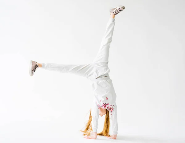 Aktivní holčička na bílém pozadí dělá handstand — Stock fotografie