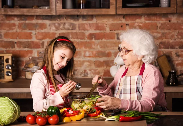 Barnbarn tjej hjälper sin mormor att laga — Stockfoto