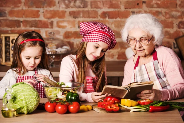 Mormor med barnbarn som använder matlagning bok — Stockfoto