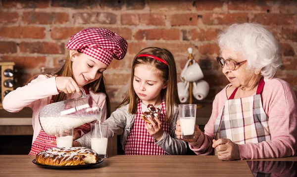 Oma mit Enkelinnen schmeckt Kuchen — Stockfoto