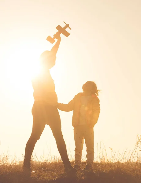 Silhouette of mother and daughter playing in the field at sunset time — Stock Photo, Image