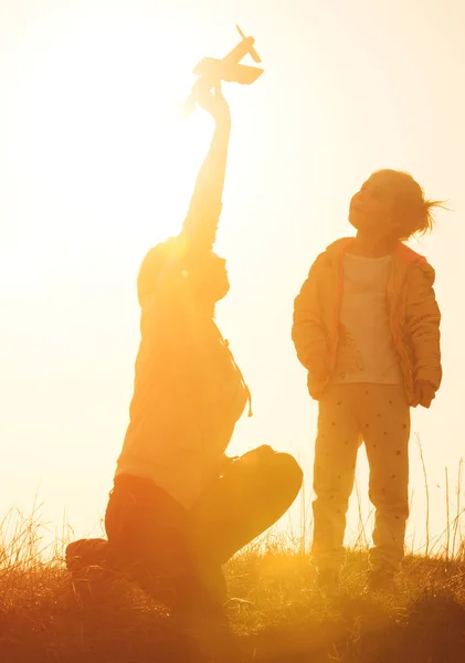 Silhueta de mãe e filha brincando no campo ao pôr do sol — Fotografia de Stock