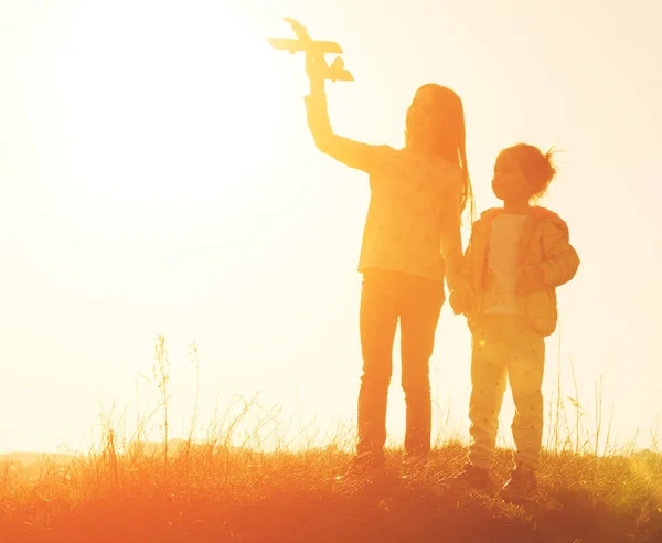 Silueta de dos hermanas jugando con el juguete del avión al atardecer — Foto de Stock