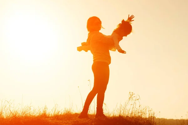 Silhouette of mother and little daughter at sunset — Stock Photo, Image