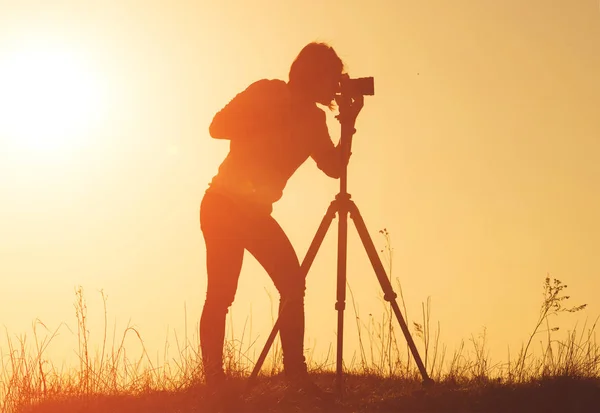 Silhueta de mulher fotógrafa fotografa paisagem de tiroteio ao pôr do sol — Fotografia de Stock