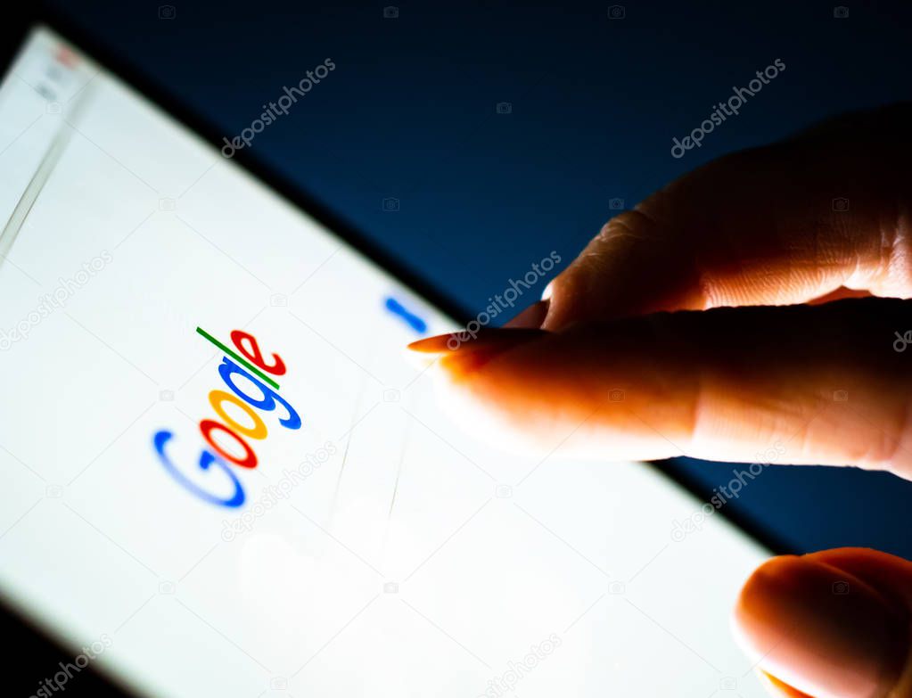 Kharkiv, Ukraine - 12 November 2018: close up girl hand using tablet with Google on the screen with a dark background