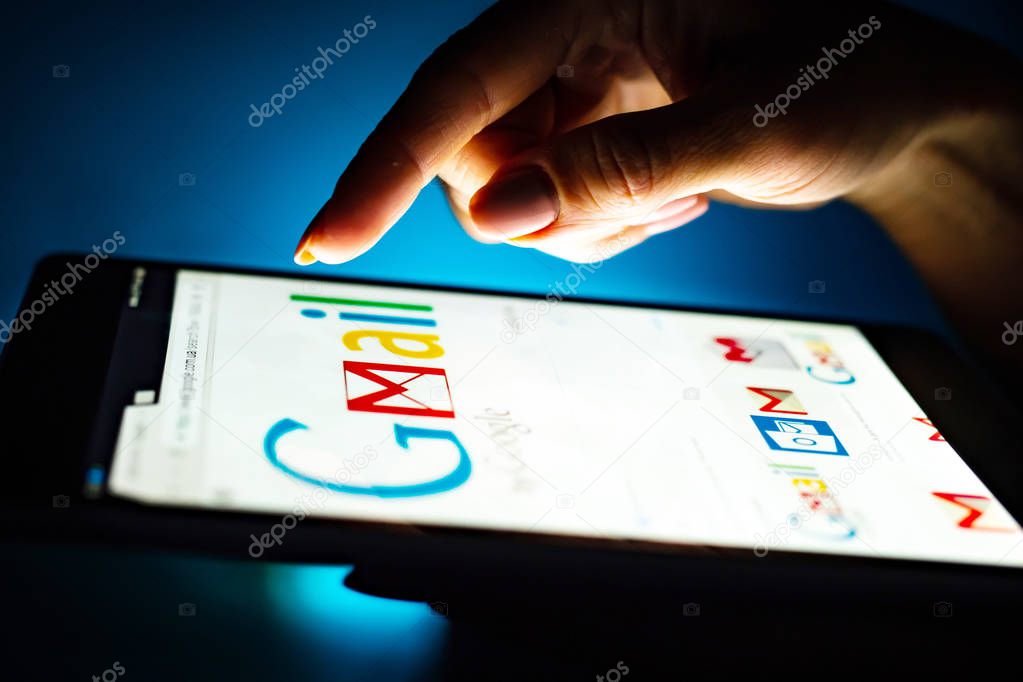 Kharkiv, Ukraine - 12 November 2018: close up girl hand using tablet with Google gmail app on the screen with a dark background
