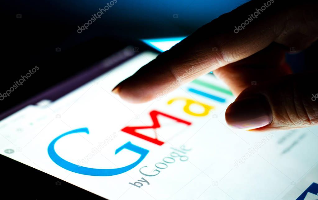 Kharkiv, Ukraine - 12 November 2018: close up girl hand using tablet with Google gmail app on the screen with a dark background