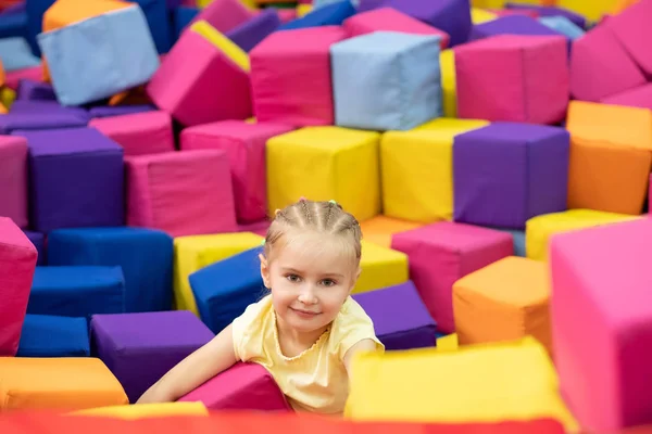 Lilla leende blond flicka sitter i lekrummet — Stockfoto