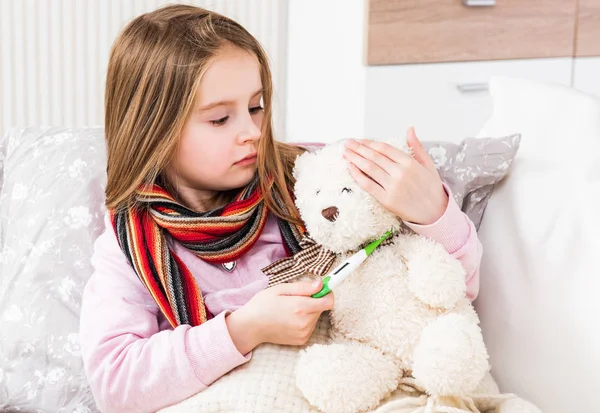 Nemocná holčička měření teddy nese teplota — Stock fotografie