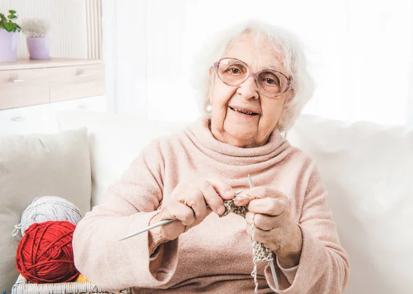 Mujer anciana sonriente tejiendo — Foto de Stock