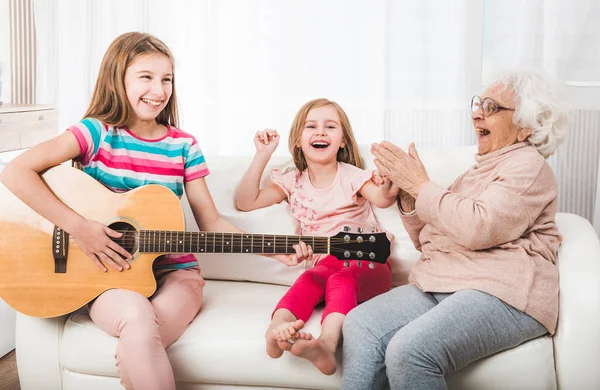 Granddaughters with grandmother listening the guitar