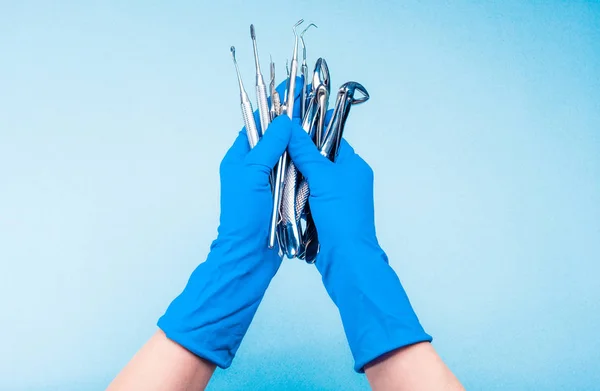 Mano en guante azul sosteniendo la cirugía herramientas dentales — Foto de Stock
