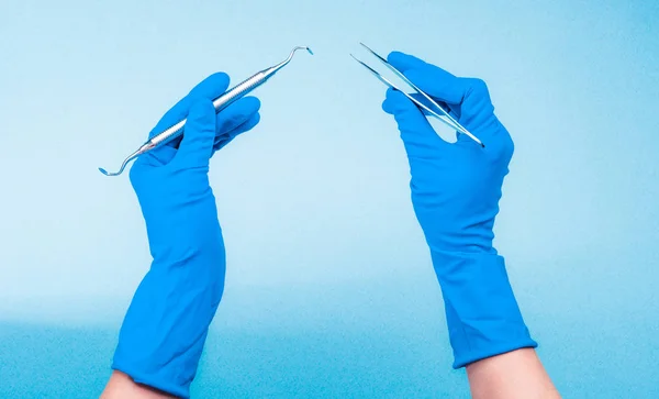 Hände in blauen Handschuhen mit zahnärztlichem Werkzeug — Stockfoto