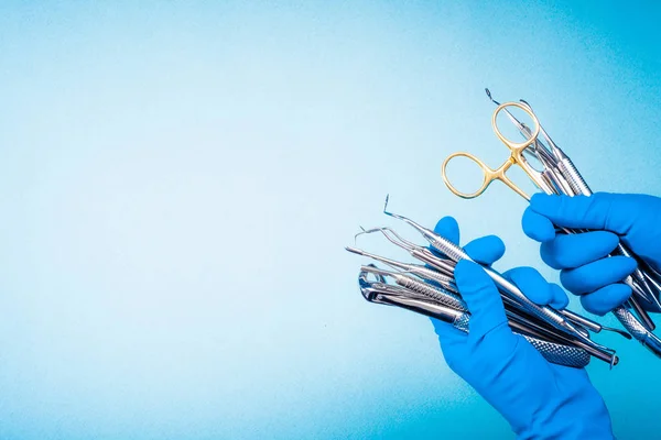Mains dans les gants bleus tenant l'équipement dentaire de chirurgie — Photo