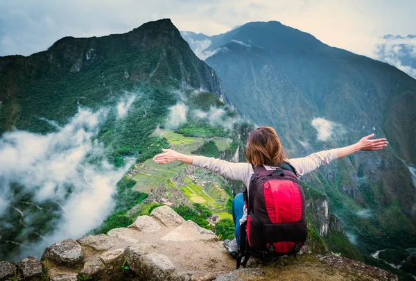 Kaya kenarına ve peyzaj Machupicchu zevk alarak üzerinde oturan kız