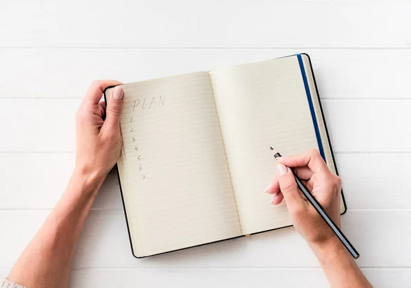 Vista dall'alto della ragazza che crea un piano nel notebook — Foto Stock