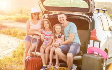 Mutlu bir aile ile bir arabanın bagajına bir seyahat etmek tatil üzerinde oturan