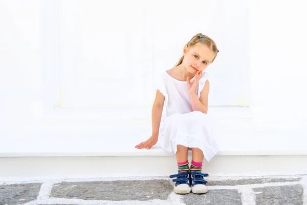 Pequeña chica bonita blong en un vestido blanco sentado al aire libre — Foto de Stock