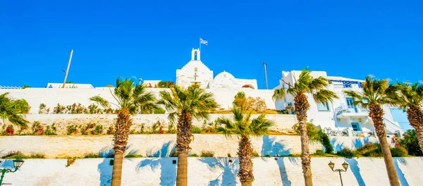 Panoramic bottom view of anchient greek church and hight palm trees in front of it on the greek street — Stock Photo, Image