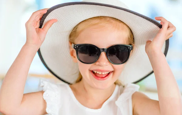 Kleines lachendes blondes Mädchen mit schwarzer Sonnenbrille — Stockfoto