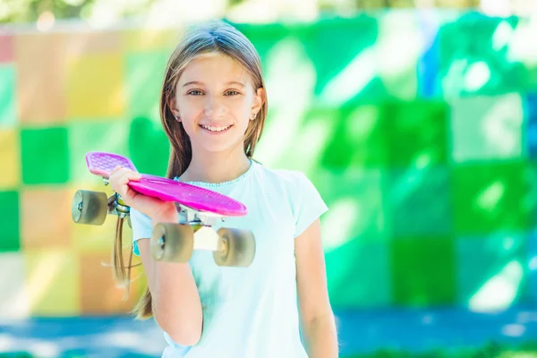 Glimlachend meisje met roze skateboard — Stockfoto