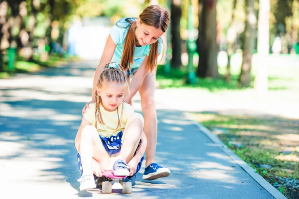 Улыбающиеся дети катаются на скейтборде в парке — стоковое фото