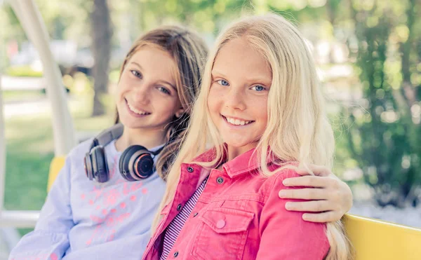 Pretty leende tonårsflickor sitter kramar tillsammans — Stockfoto