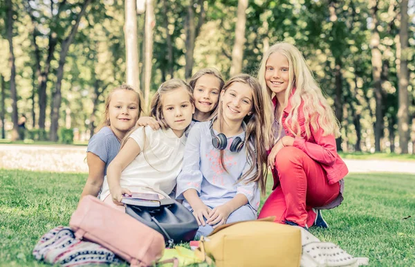 Красивые улыбающиеся маленькие девочки сидят вместе в парке — стоковое фото