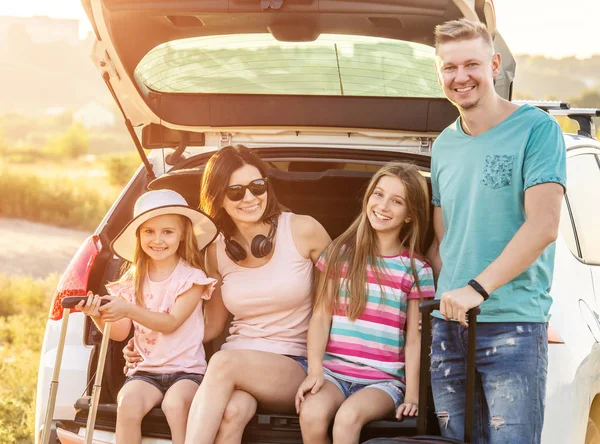 Happy family sitting on a trunk of a car with on a travel vacation